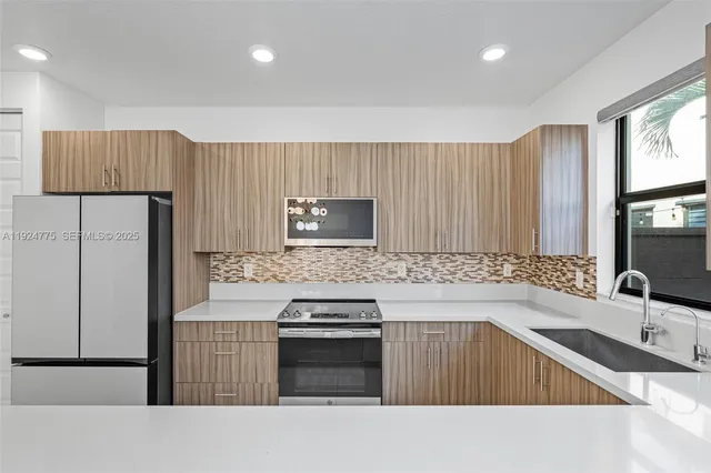 a view of a kitchen with granite countertop cabinets a counter top and stainless steel appliances