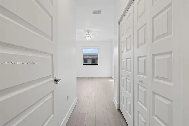a view of a room with wooden floor and a ceiling fan