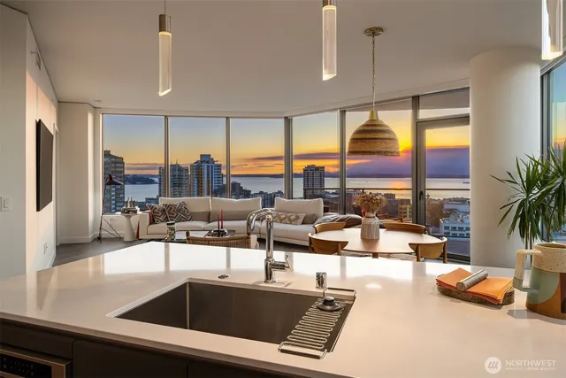 a living room with furniture kitchen view and large windows