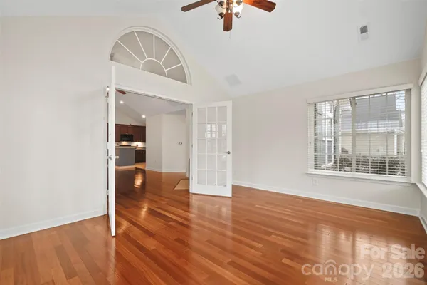 a view of an empty room with window and wooden floor