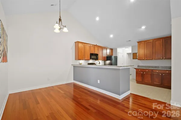 a kitchen with stainless steel appliances granite countertop a refrigerator a sink dishwasher a stove and white countertops with wooden floor