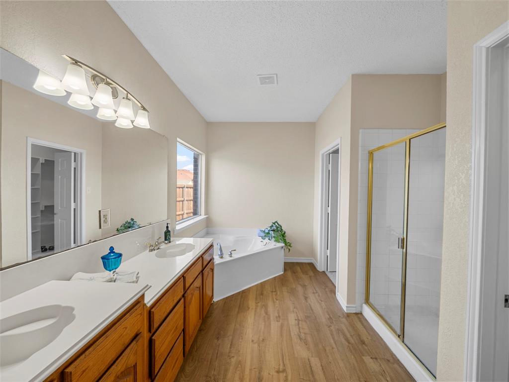 741 Aspen Court Allen, TX 75002 - Photo 24 of 40 Primary Bathroom with a stall shower, double vanity, a garden tub, light wood-type flooring, and a textured ceiling