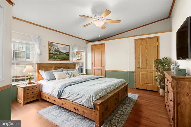 a bedroom with bed a flat tv screen and a dresser with wooden floor