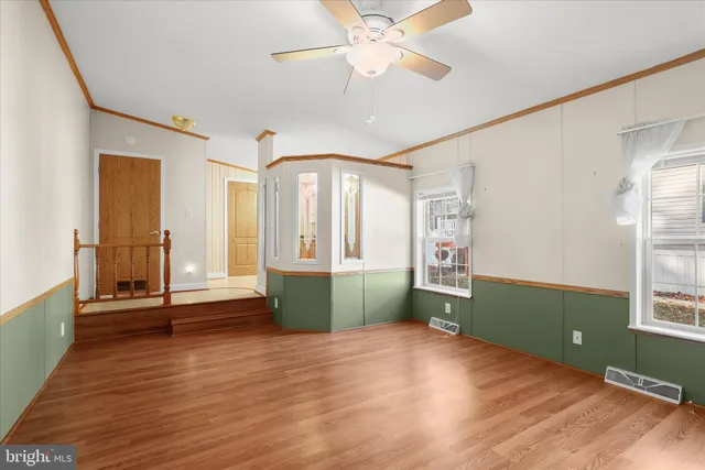 a view of an empty room with window and wooden floor