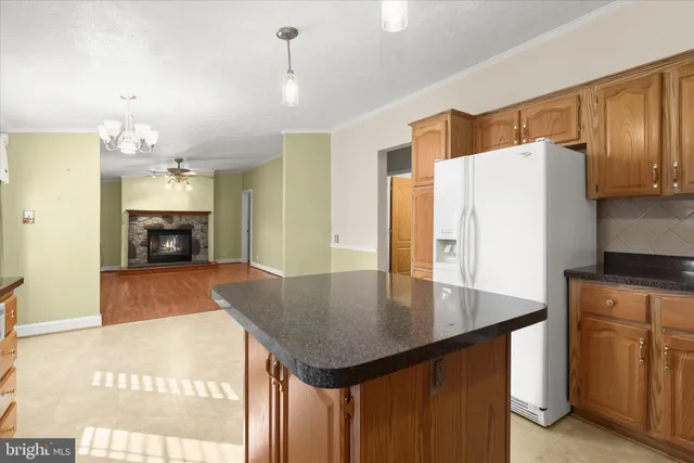 a kitchen with granite countertop a refrigerator a stove a sink dishwasher and wooden cabinets with wooden floor