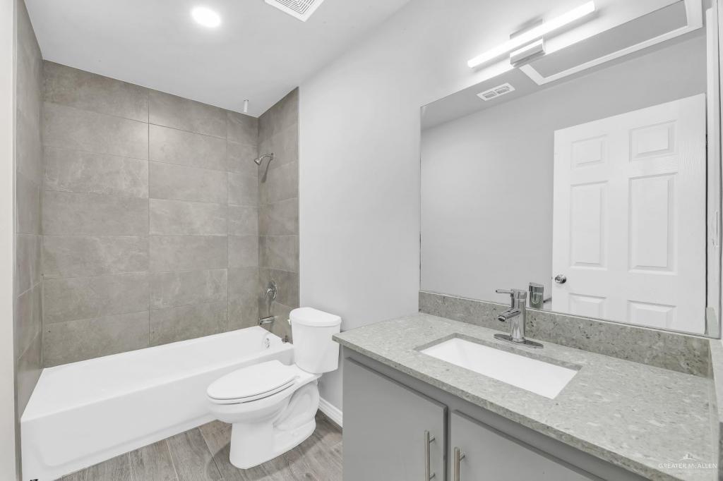 1001 West Sunset Valley Street, Unit 2 Alton, TX 78573 - Photo 12 of 13 a bathroom with a granite countertop sink a toilet a mirror and shower