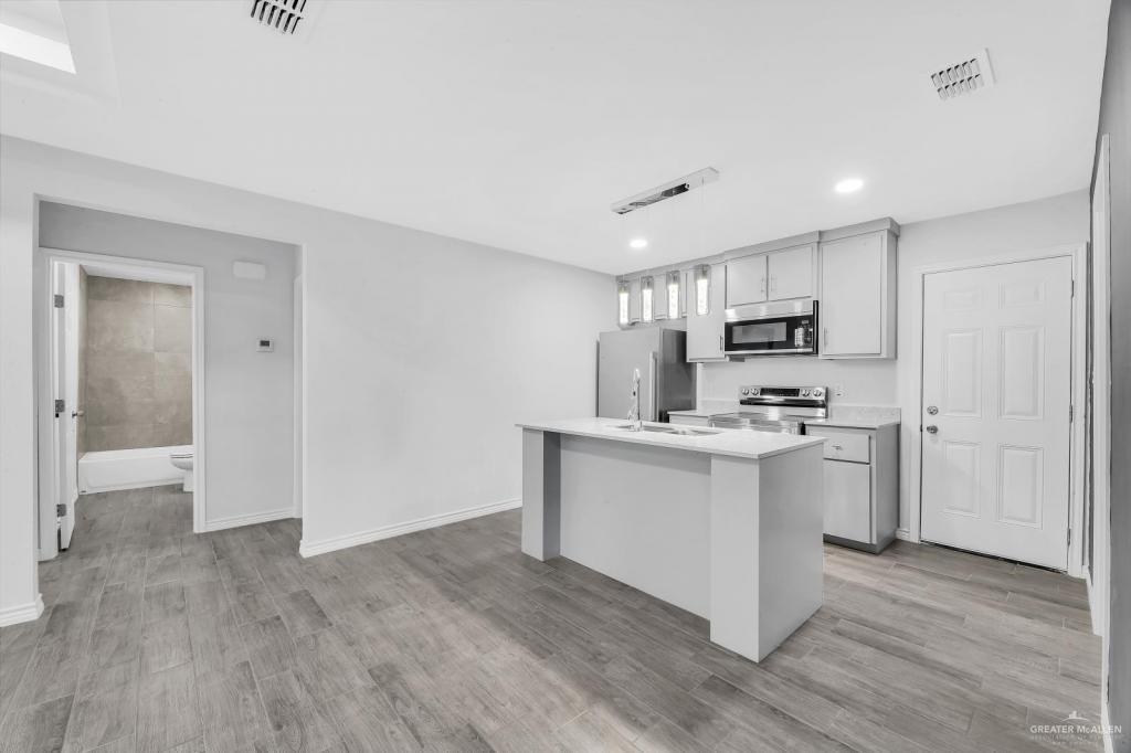 1001 West Sunset Valley Street, Unit 2 Alton, TX 78573 - Photo 4 of 13 a kitchen with kitchen island a sink cabinets and wooden floor