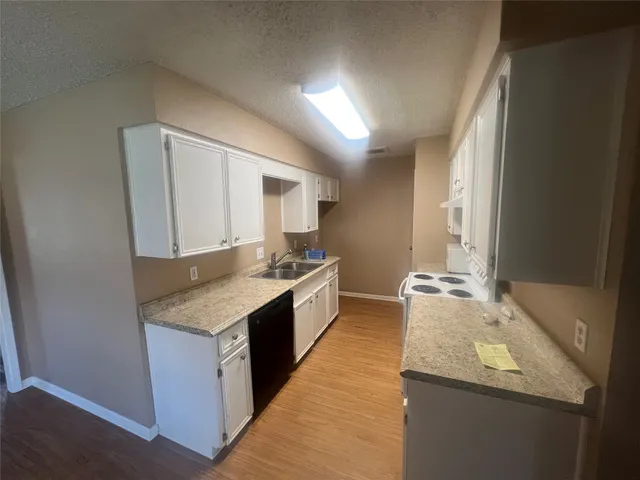 a large kitchen with granite countertop a sink and dishwasher a stove with wooden floor