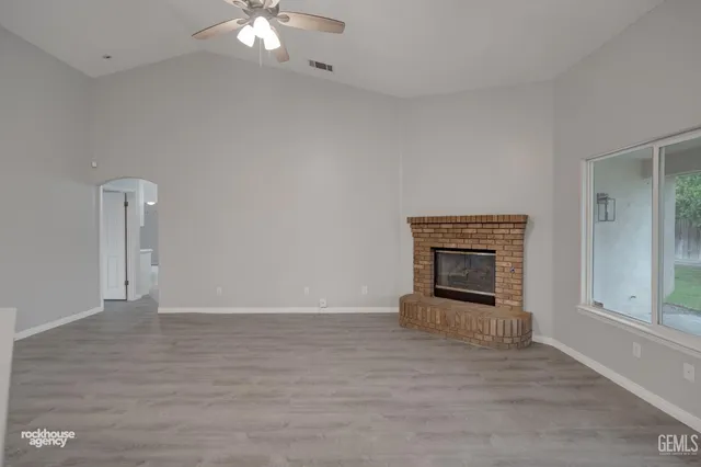 a view of a livingroom with wooden floor a ceiling fan and windows
