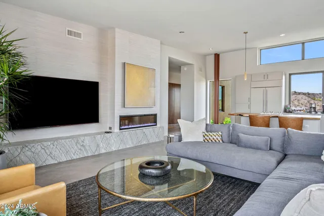 a living room with stainless steel appliances kitchen island granite countertop a table chairs in it and a wooden floor