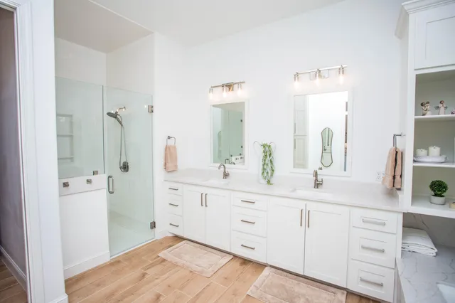 a view of a hallway with wooden floor and a bathroom