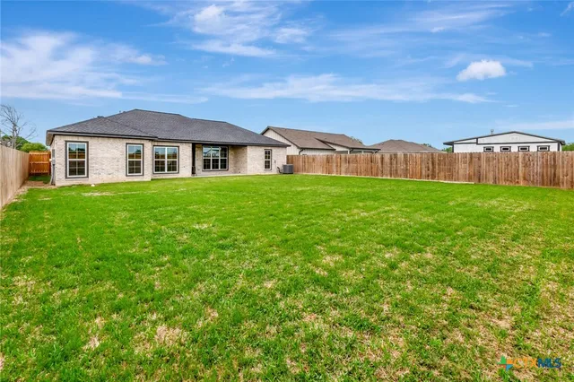 a view of a big house with a big yard and large trees