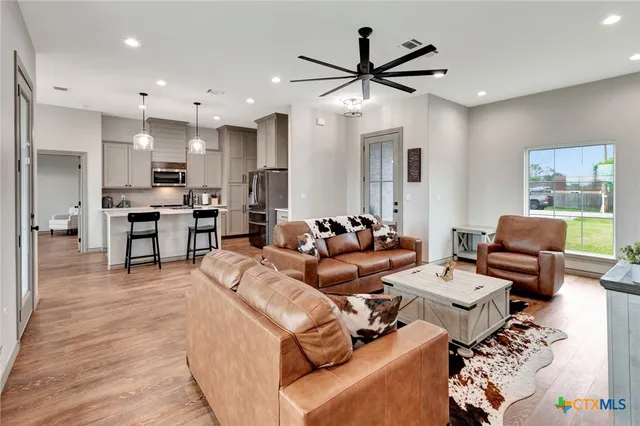 a living room with furniture kitchen view and a wooden floor