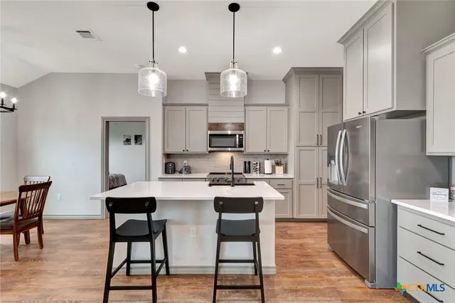 a kitchen with stainless steel appliances a dining table chairs stove and refrigerator