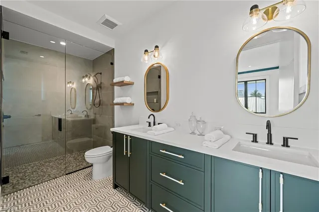 a bathroom with a toilet sink double vanity and mirror