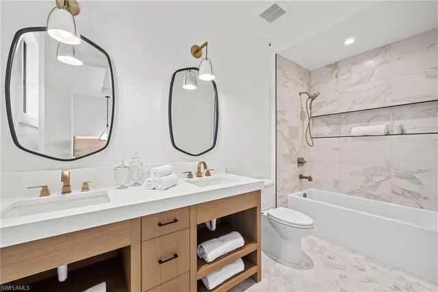 a bathroom with a double vanity sink double mirror bathtub and toilet