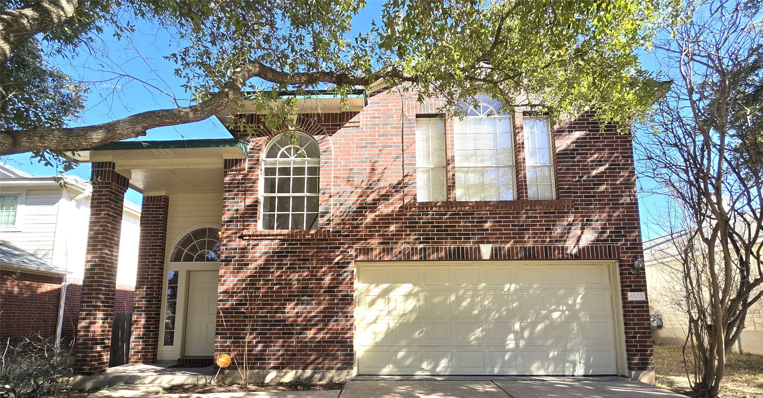 View of front of property with brick siding, driveway, and an attached garage