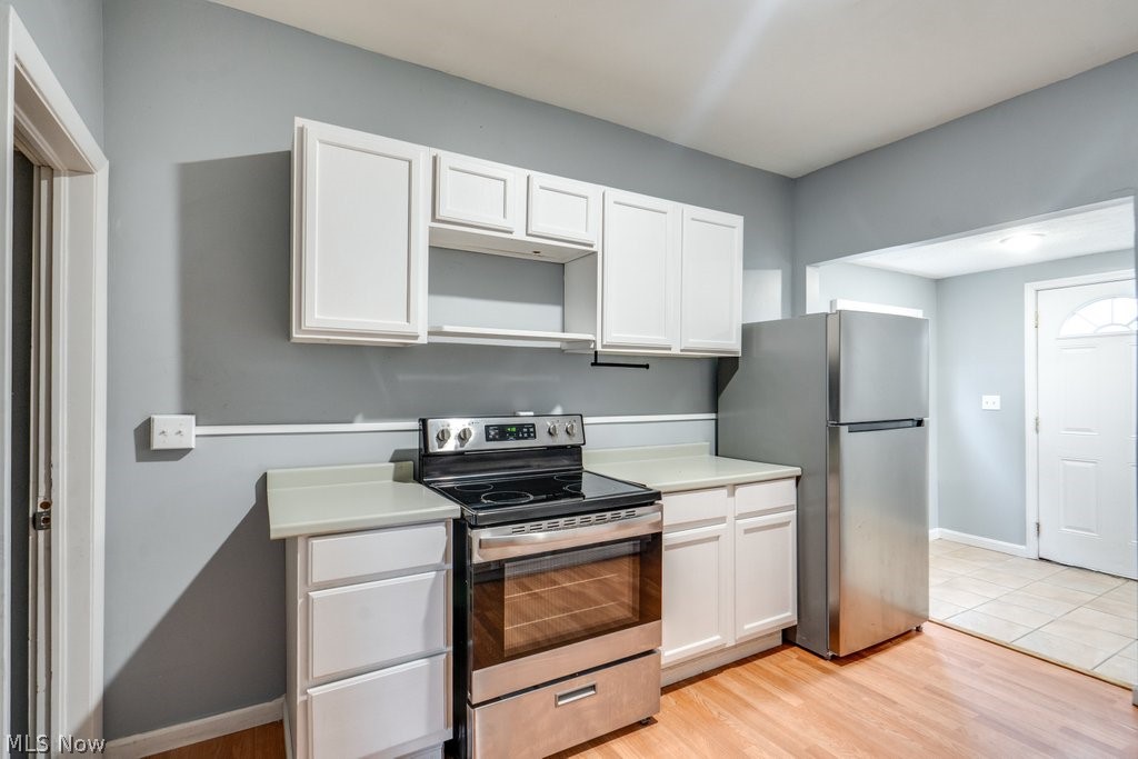 1607 9th Street Southwest Canton, OH 44706 - Photo 18 of 41 Kitchen featuring wood-finish flooring, white cabinetry, stainless steel appliances, light-toned countertops, and an arched doorway