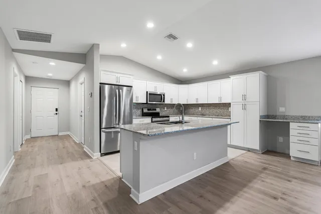 a kitchen with stainless steel appliances granite countertop a refrigerator and a stove top oven