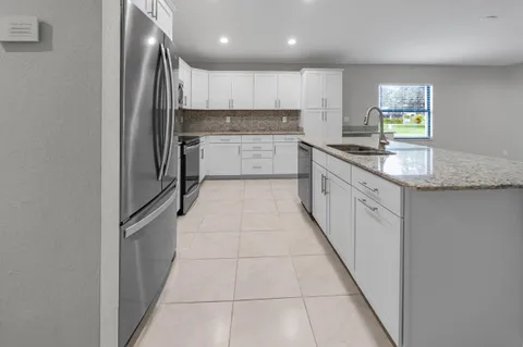 a large kitchen with stainless steel appliances granite countertop a sink and cabinets