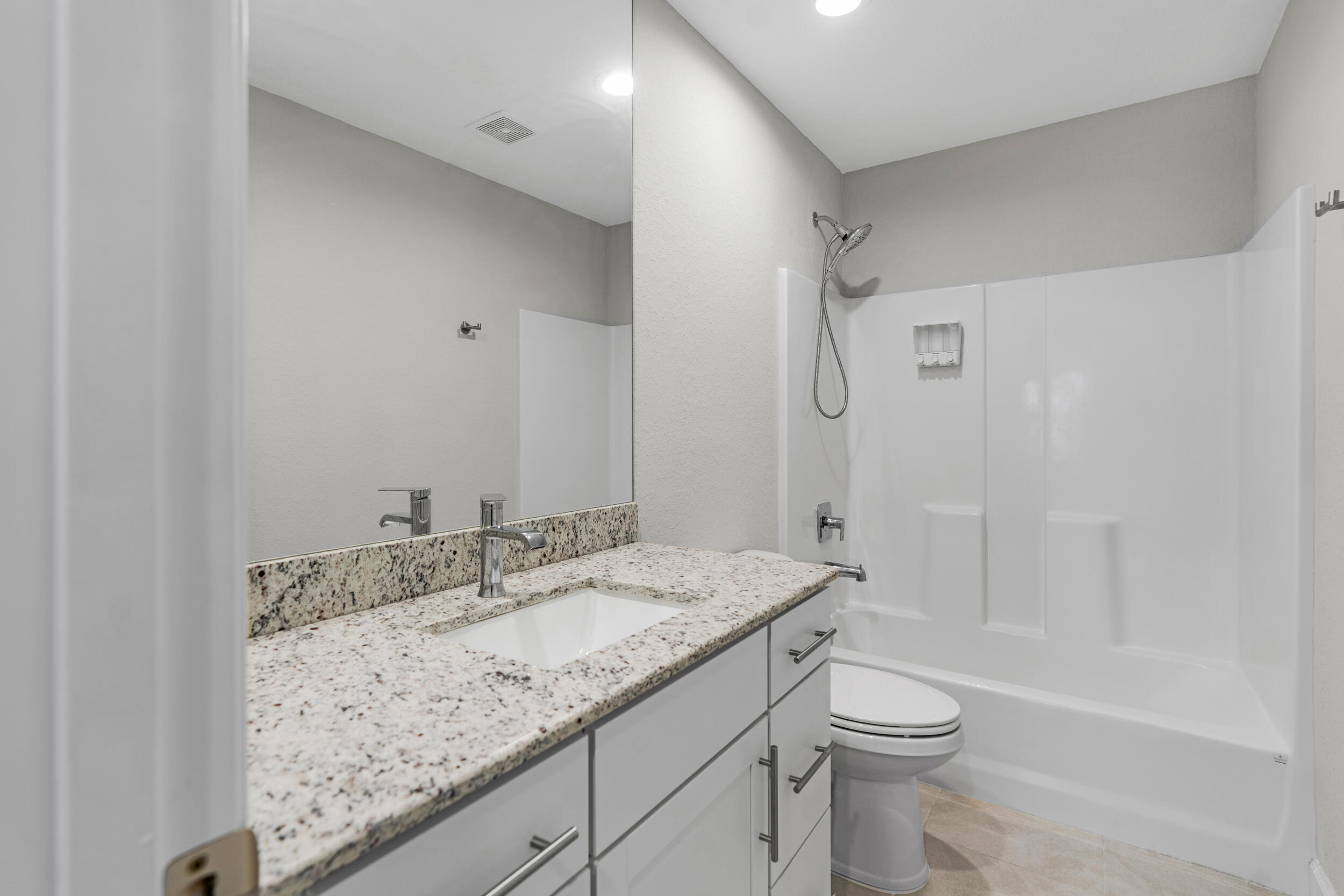 14533 Dulce Real Avenue Fort Pierce, FL 34951 - Photo 26 of 42 a bathroom with a granite countertop sink a toilet and shower