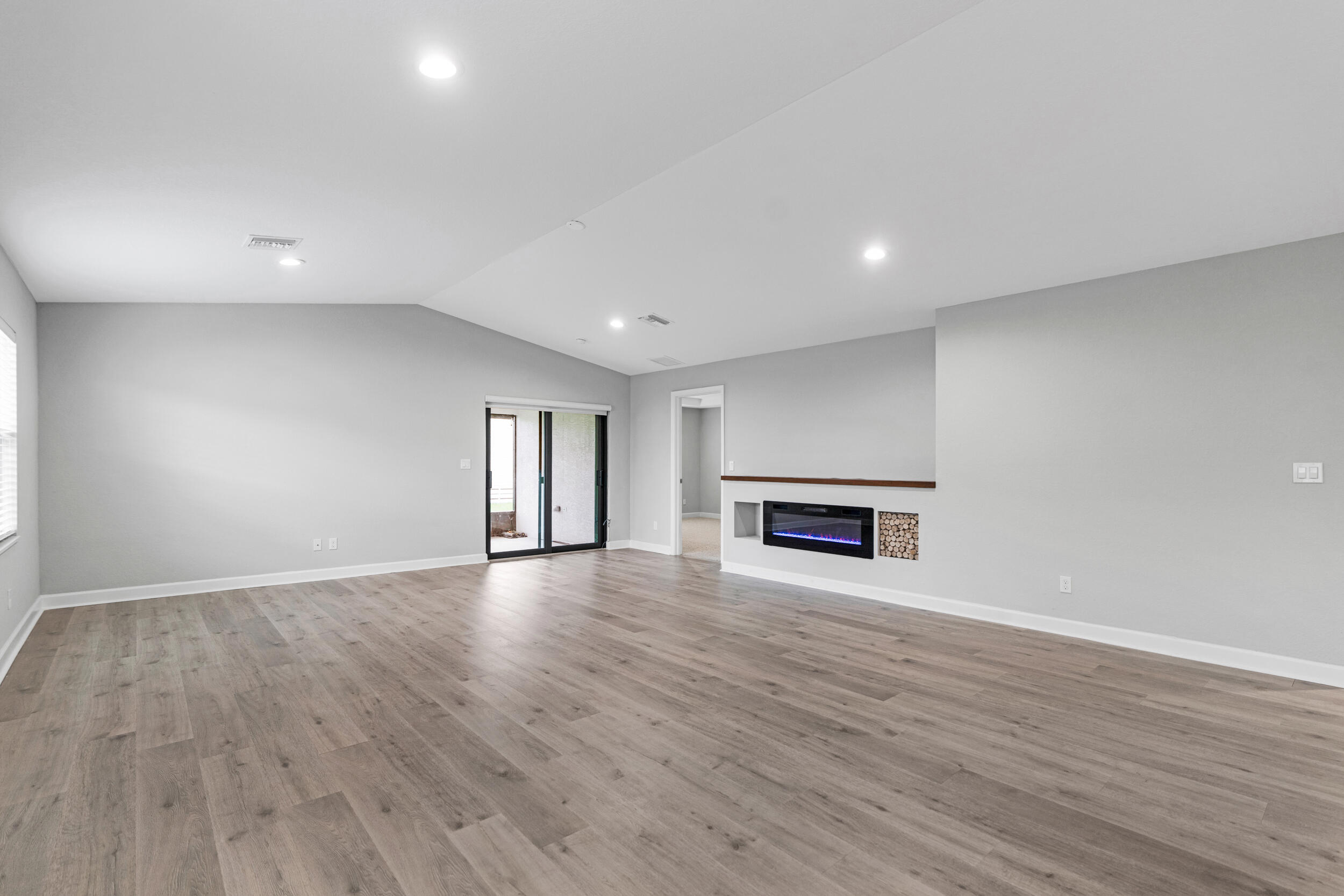 14533 Dulce Real Avenue Fort Pierce, FL 34951 - Photo 8 of 42 an empty room with wooden floor fireplace and windows