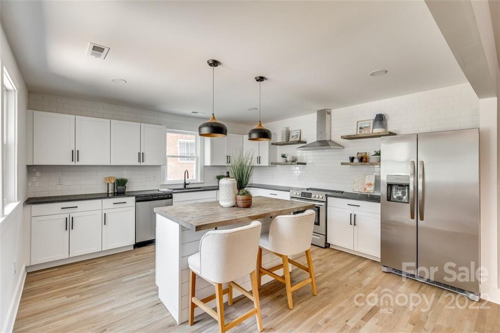 1321 Enderly Road Charlotte, NC 28208 - Photo 11 of 26 a kitchen with stainless steel appliances granite countertop a sink a stove a refrigerator and island with wooden floor