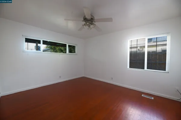 an empty room with a ceiling fan and window