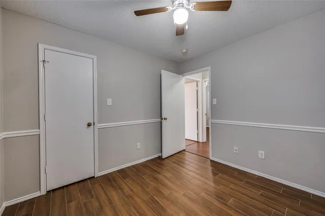 an empty room with wooden floor chandelier and windows