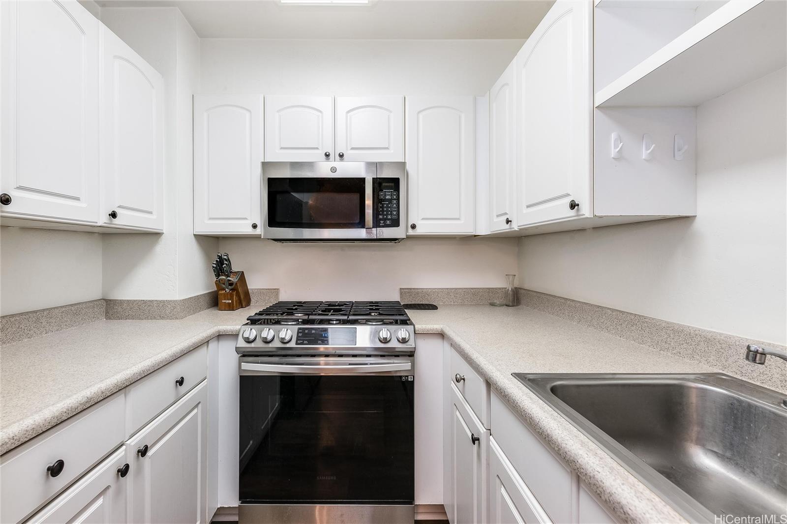 87-119 Helelua Street, Unit F202 Waianae, HI 96792 - Photo 8 of 25 a kitchen with stainless steel appliances granite countertop grey cabinets a stove a sink and dishwasher