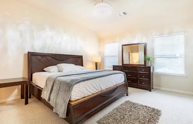 a bedroom with a bed and dresser with mirror