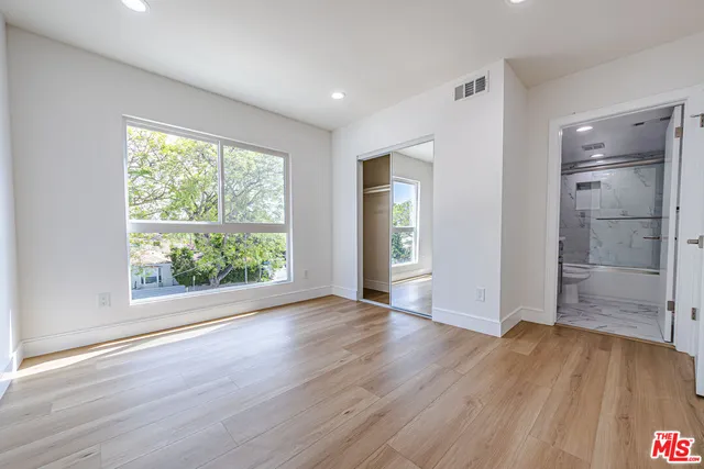 an empty room with wooden floor cabinet and windows