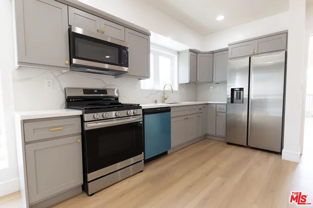 a kitchen with stainless steel appliances granite countertop a stove a refrigerator and a microwave