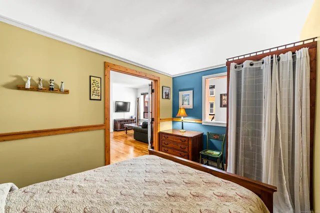 a bedroom with a bed and a dresser next to a window