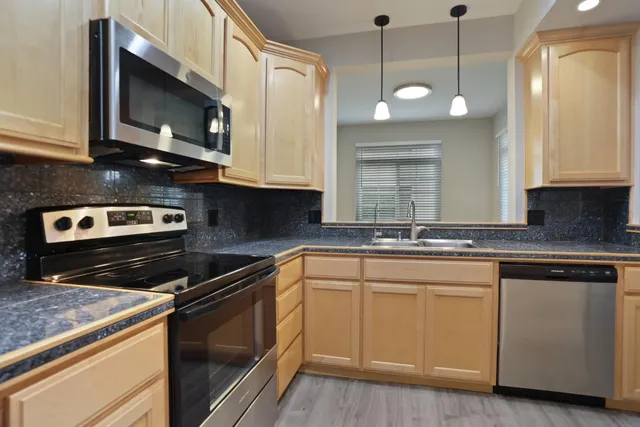 a kitchen with stainless steel appliances granite countertop a sink a stove and a microwave