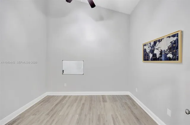 an empty room with wooden floor chandelier fan and windows