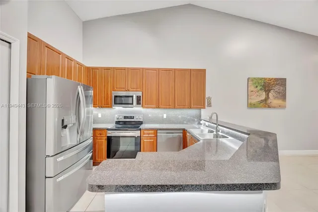 a kitchen with stainless steel appliances granite countertop a refrigerator a stove top oven a sink dishwasher and white cabinets next to a window