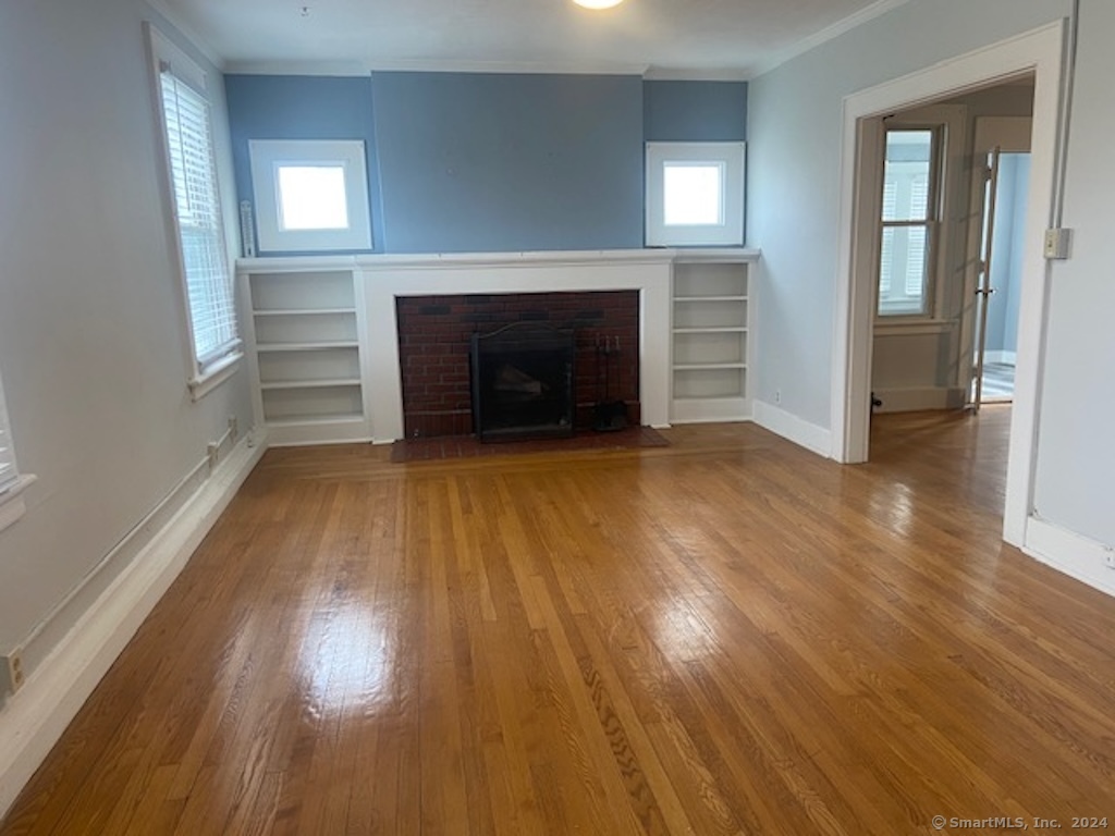 279 Wakelee Avenue Ansonia, CT 06401 - Photo 12 of 23 an empty room with wooden floor fireplace and windows