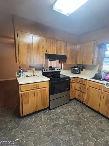 a kitchen with stainless steel appliances granite countertop a sink a stove a refrigerator with grey cabinets