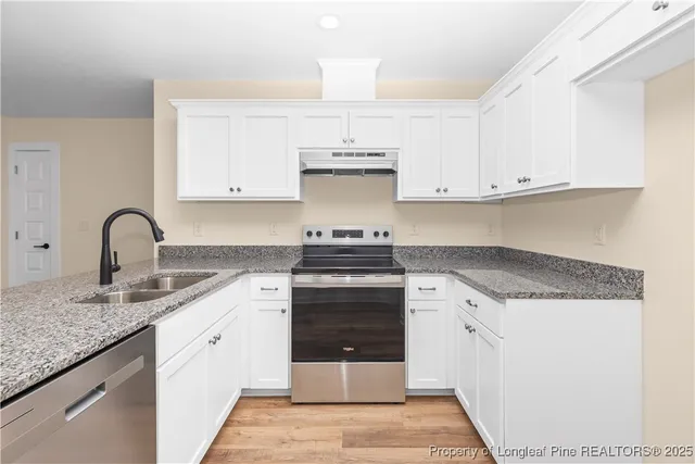 a kitchen with stainless steel appliances granite countertop a stove and white cabinets