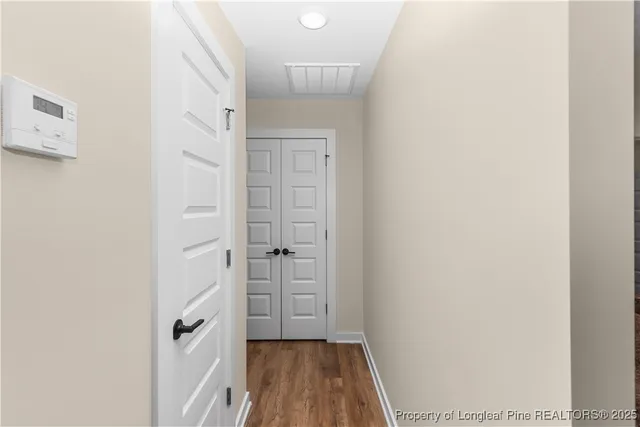a view of a hallway with wooden floor and closet