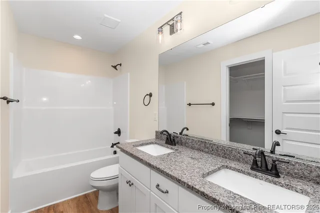 a bathroom with a granite countertop sink toilet mirror and bathtub