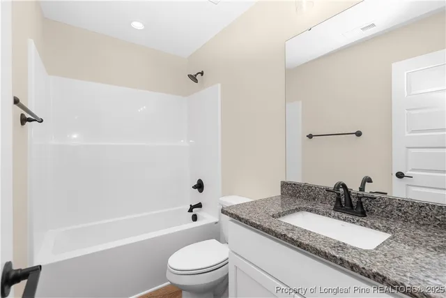 a bathroom with a granite countertop sink toilet mirror and shower
