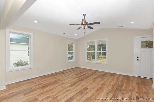 a view of an empty room with a window and wooden floor