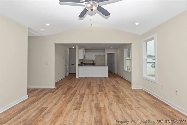 a view of empty room with wooden floor and ceiling fan