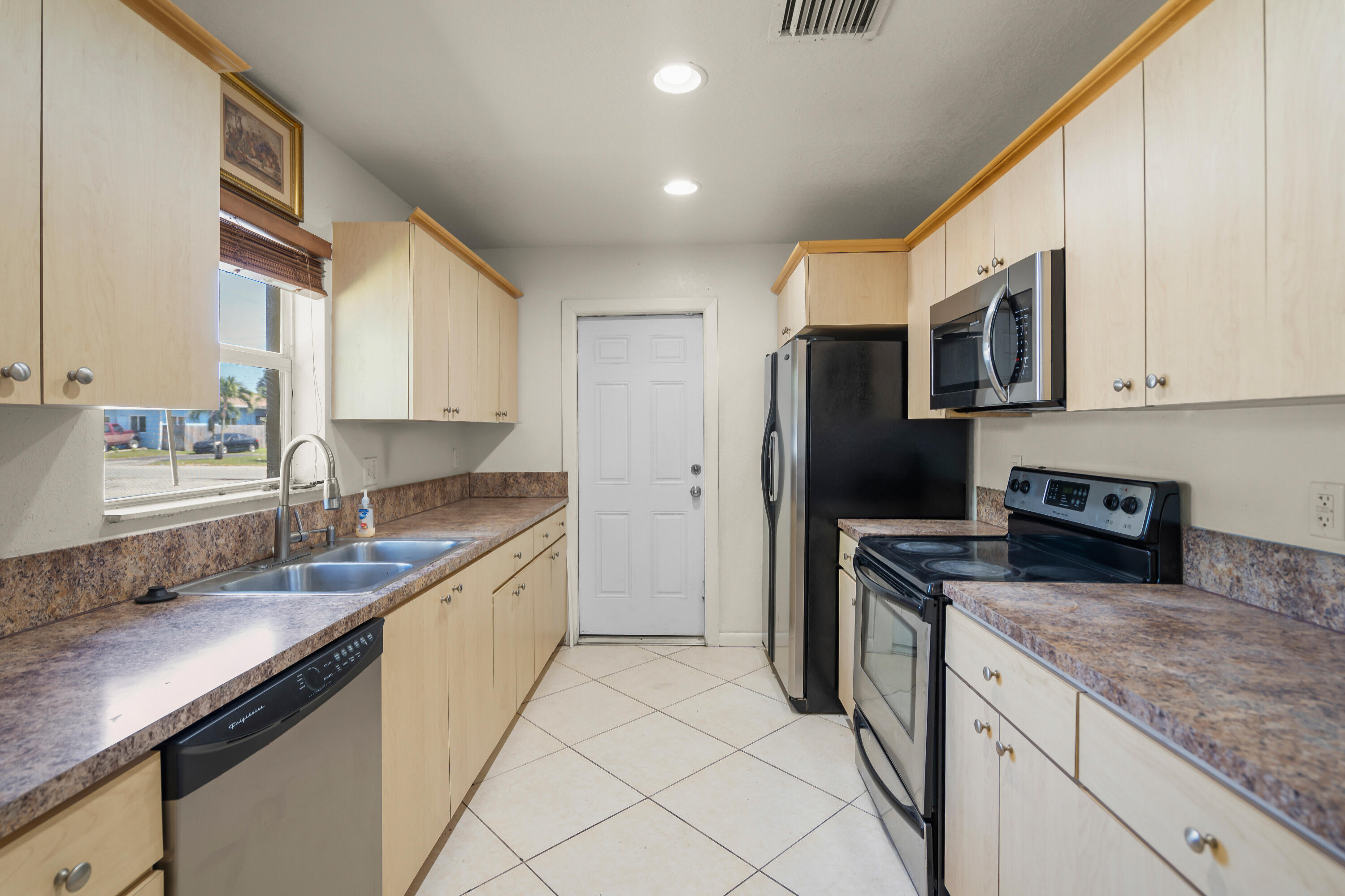 2241 Northwest 3rd Street Pompano Beach, FL 33069 - Photo 8 of 27 a kitchen with stainless steel appliances granite countertop a sink stove microwave and refrigerator