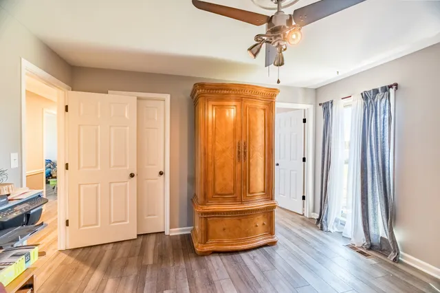 a view of empty room with wooden floor and fan