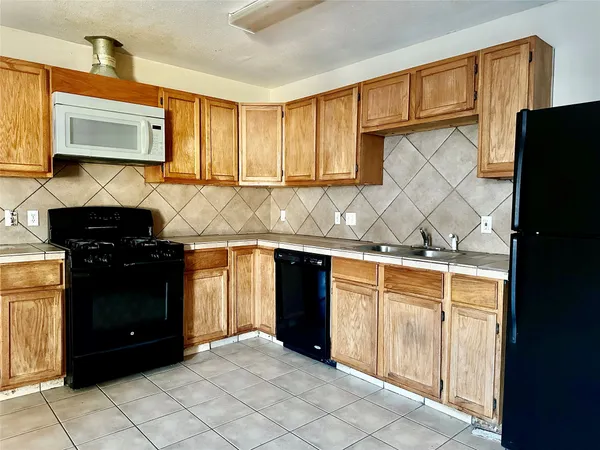 a kitchen with granite countertop a refrigerator a stove and a microwave