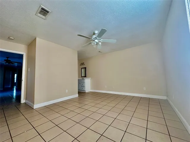 a view of an empty room and chandelier fan