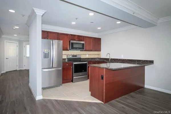 a kitchen with stainless steel appliances granite countertop a refrigerator a stove a sink and a microwave